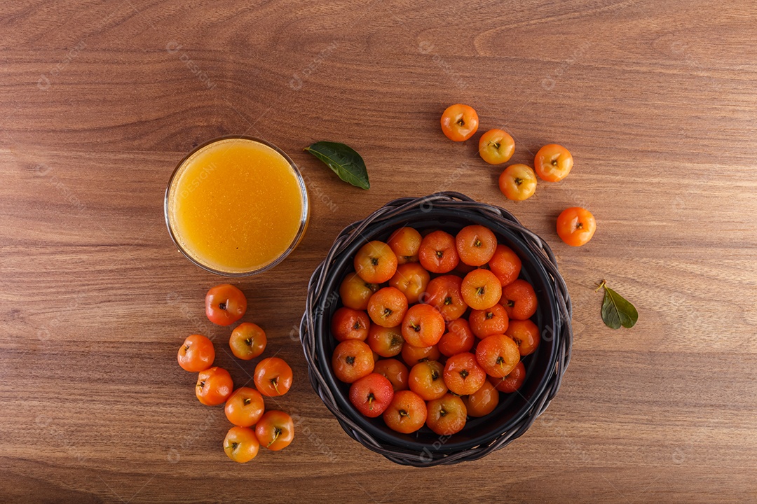 Suco de acerola e acerolas cruas na mesa de madeira na natureza.