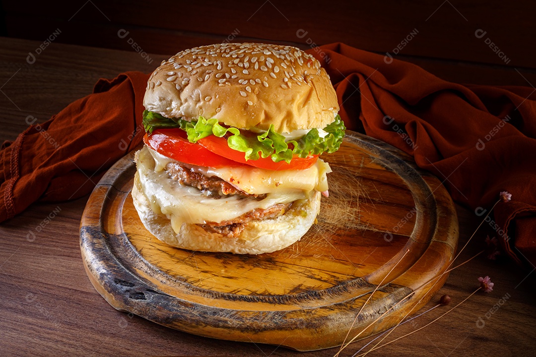 Delicioso hambúrguer na mesa de madeira, especiarias e tecido marrom.