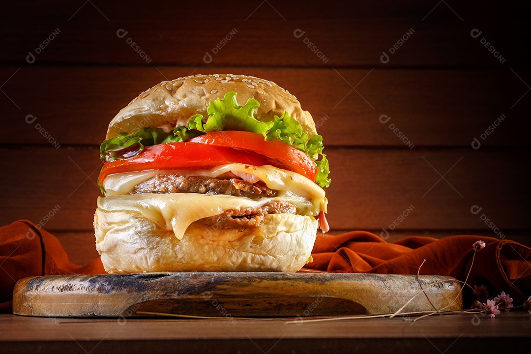 Delicioso hambúrguer na mesa de madeira, especiarias e tecido marrom.