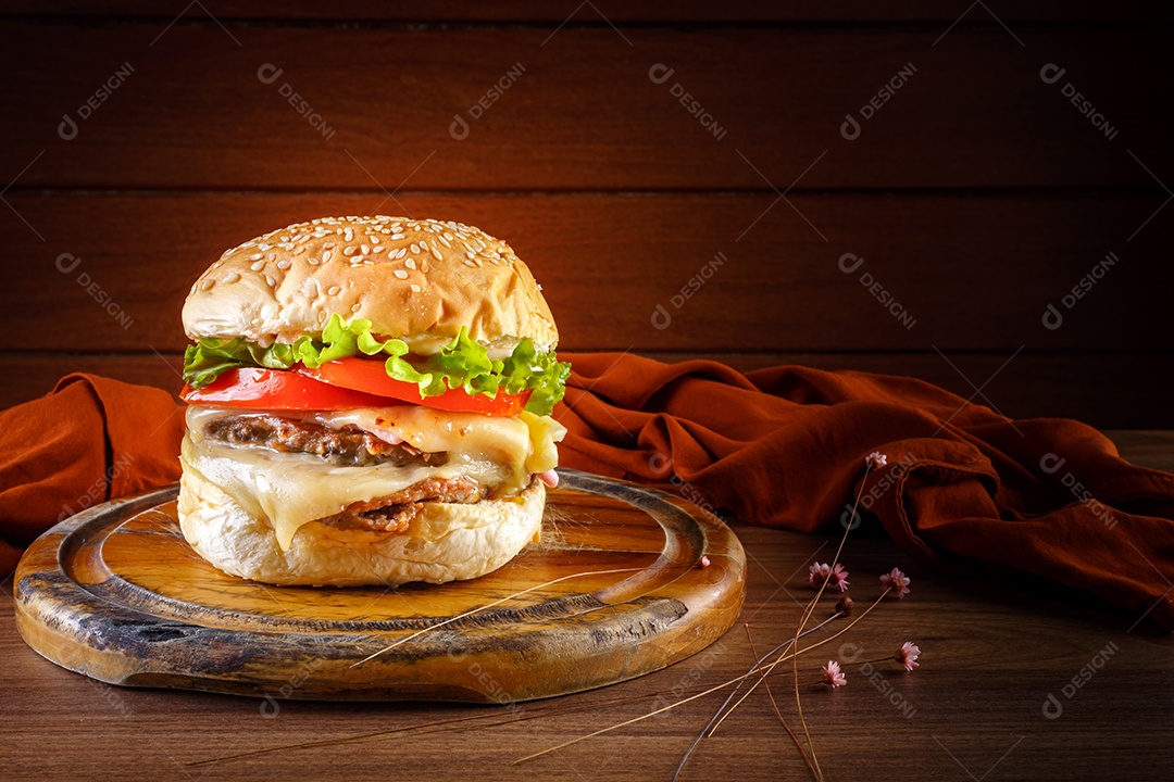 Delicioso hambúrguer na mesa de madeira, especiarias e tecido marrom.