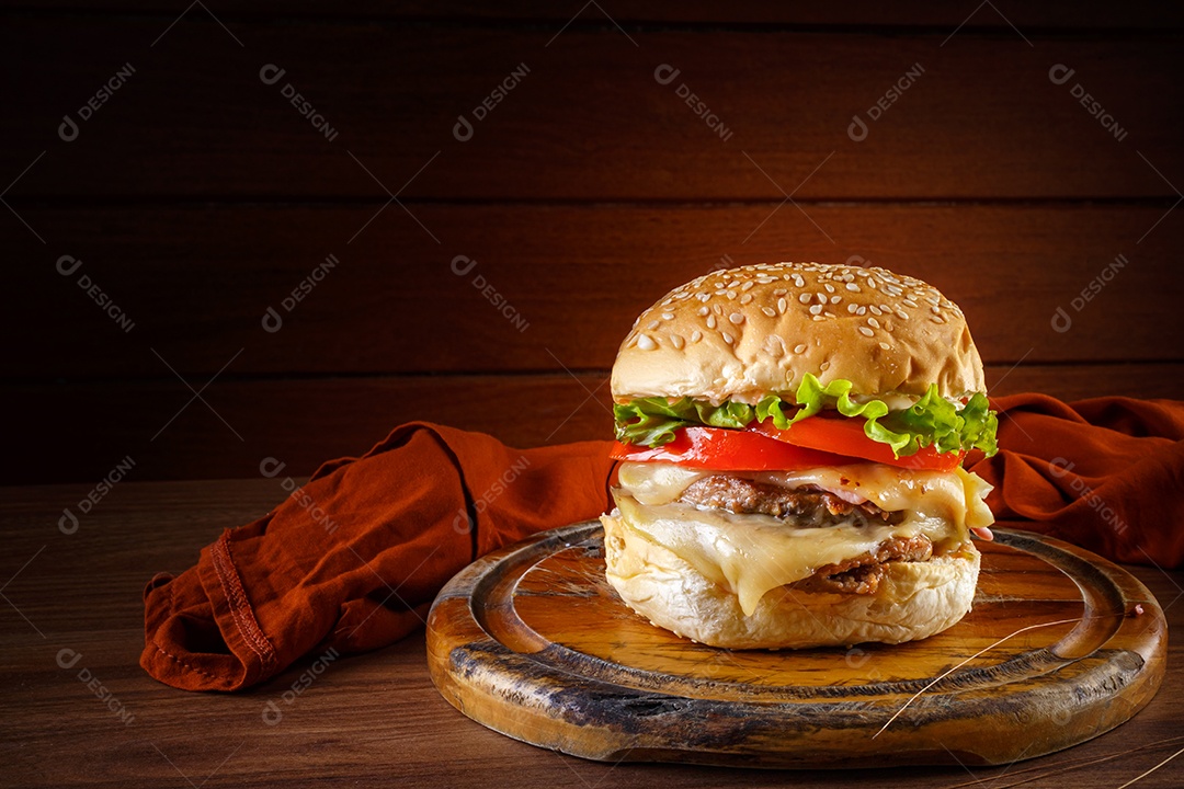 Delicioso hambúrguer na mesa de madeira, especiarias e tecido marrom.