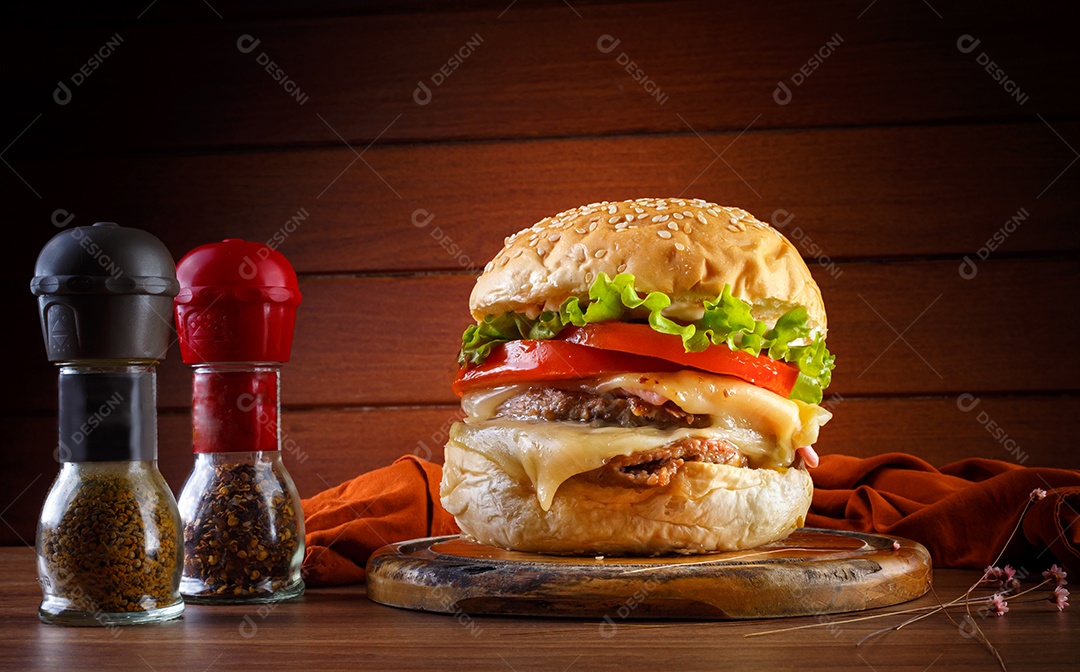 Delicioso hambúrguer na mesa de madeira, especiarias e tecido marrom.