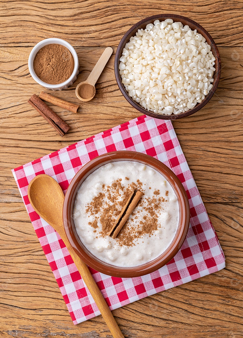 Canjica ou munguza, típico creme doce de milho branco brasileiro com canela sobre mesa de madeira.
