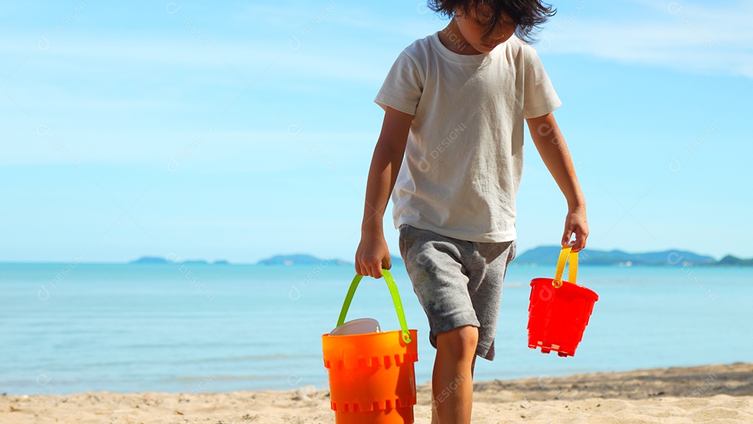 Menino bonito andando jogando água e areia na praia