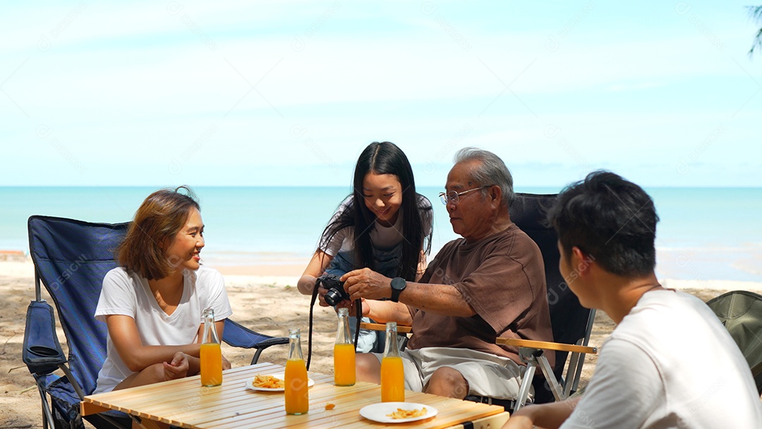 Família feliz olhando a foto na câmera tirando memórias do lado de fora na praia