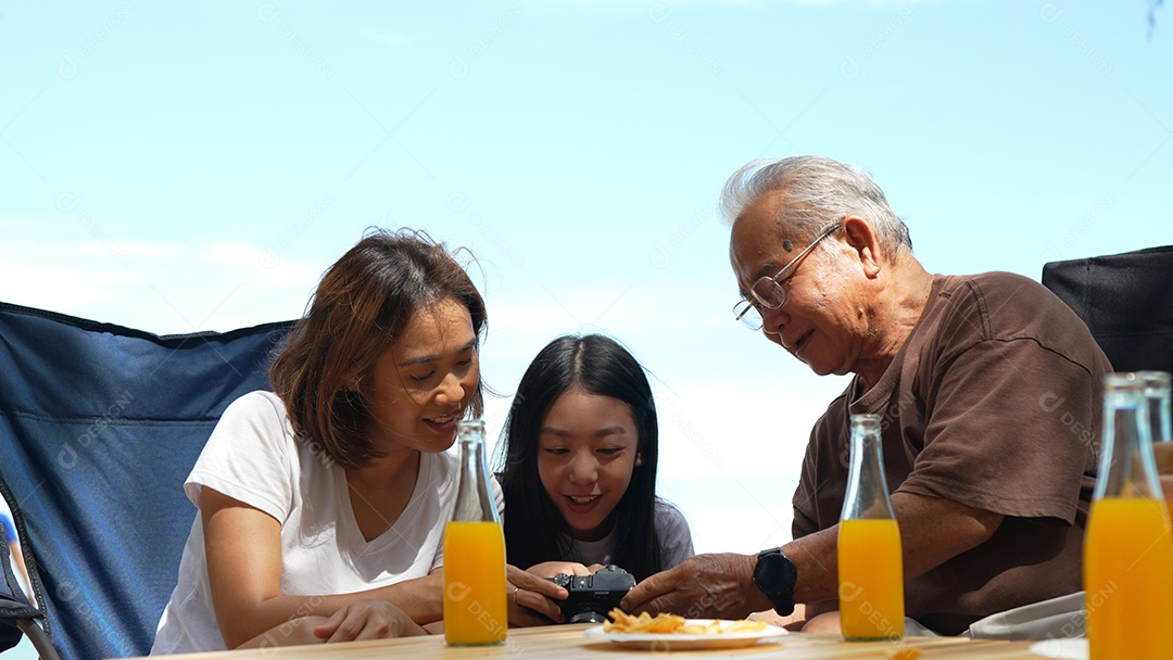 Família feliz olhando a foto na câmera tirando memórias do lado de fora na praia