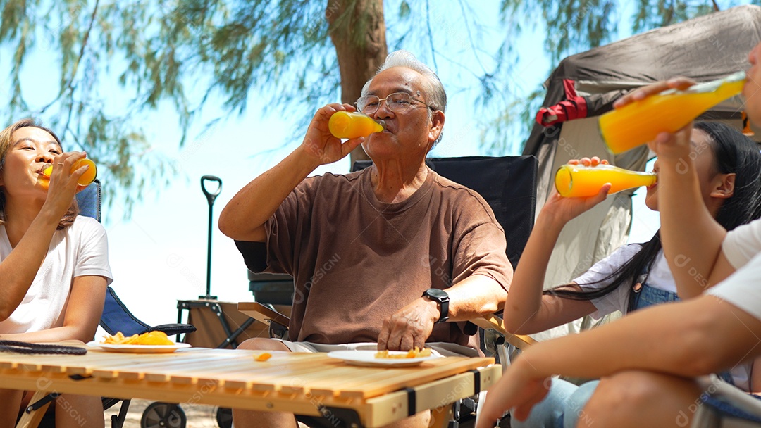 Grupo de pessoas familiares acampando na praia bebendo refresco de suco