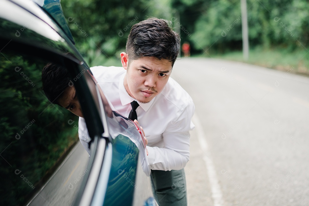 Empresário asiático empurrando carro quebrado na estrada da montanha