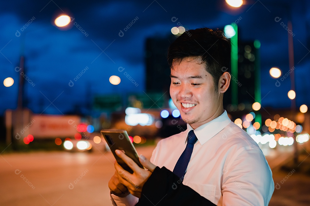 Empresário asiático usa telefone celular, smartphone depois do trabalho andando pela rua da cidade