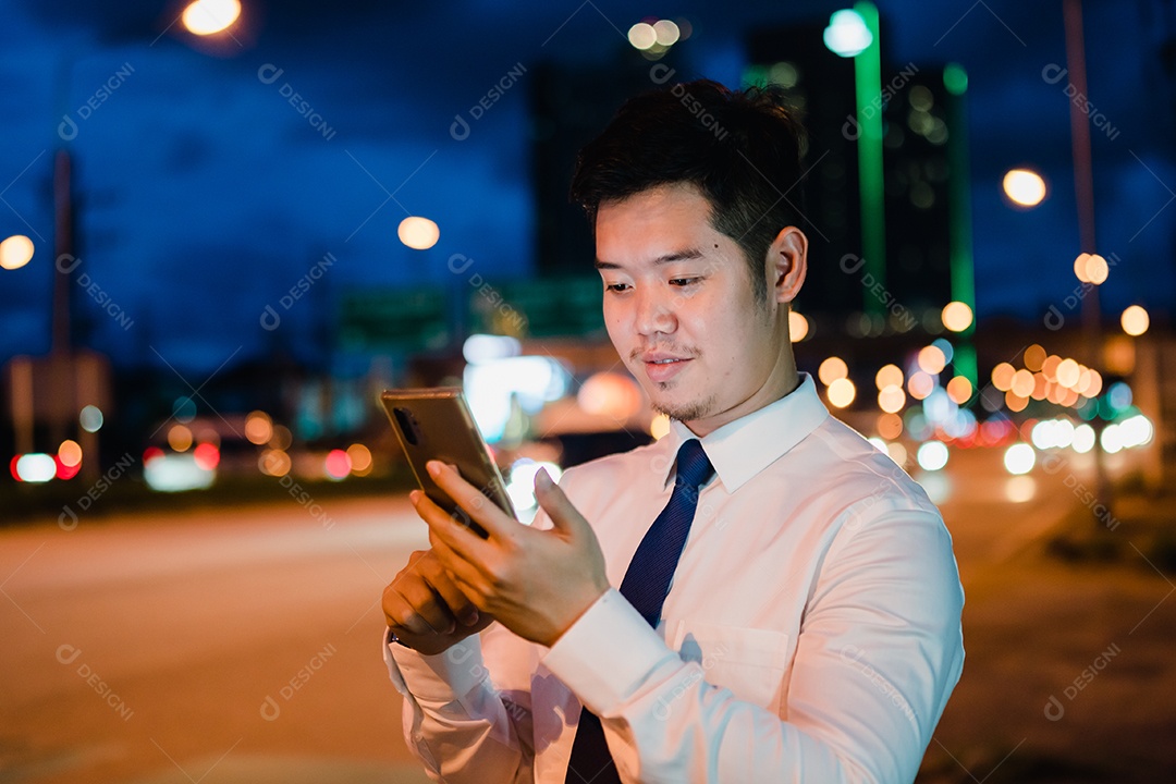 Empresário asiático usa telefone celular, smartphone depois do trabalho andando pela rua da cidade