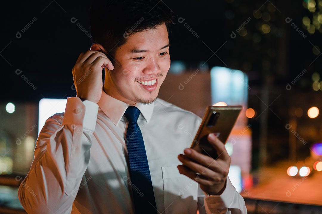 Empresário asiático usa telefone celular, smartphone depois do trabalho andando pela rua da cidade