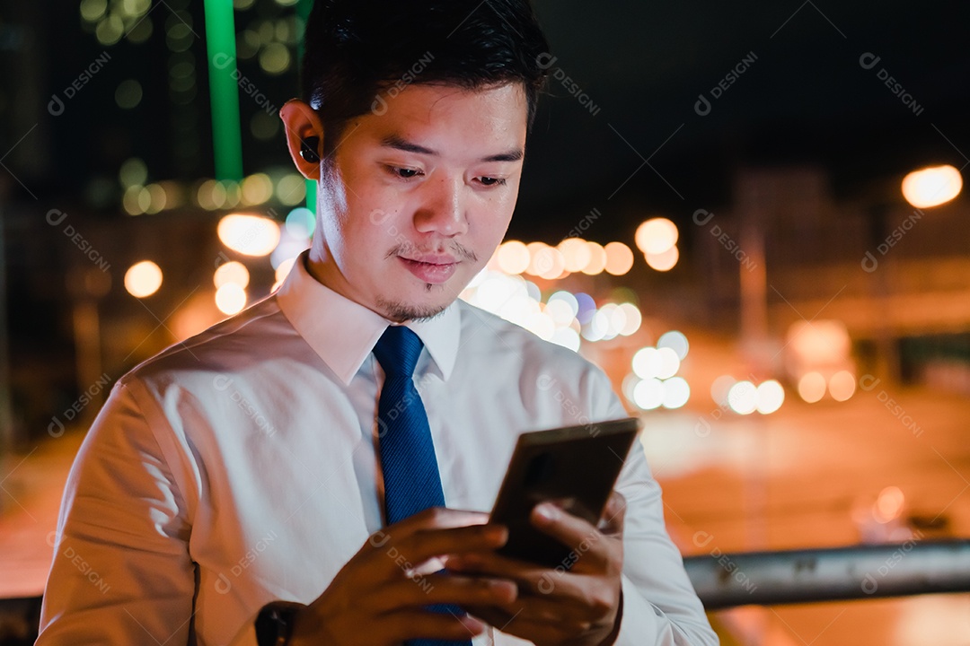 Empresário asiático usa telefone celular, smartphone depois do trabalho andando pela rua da cidade