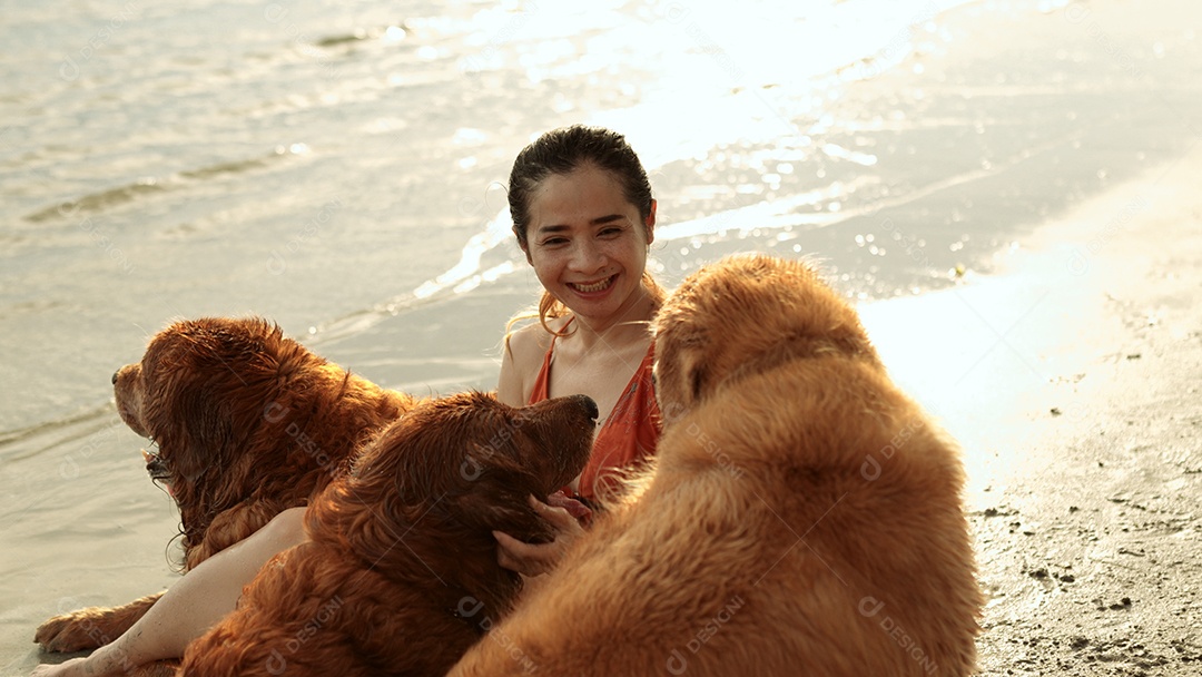 A mulher feliz com o grupo de cães que senta-se relaxa e descansa aprecia a liberdade na praia
