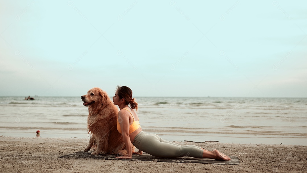 Mulher saudável asiática fazendo exercícios de ioga com cachorro de estimação na praia