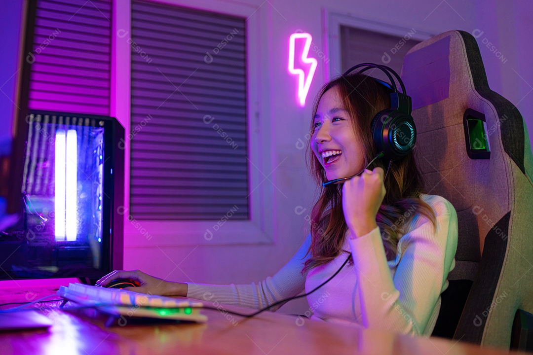 Jogador asiático jogando videogame online ganhando entusiasmo no PC com efeito de iluminação