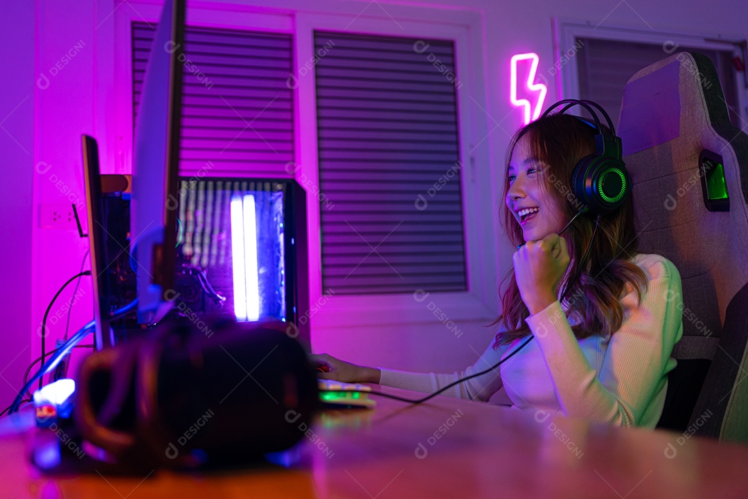 Jogador asiático jogando videogame online ganhando entusiasmo no PC com efeito de iluminação