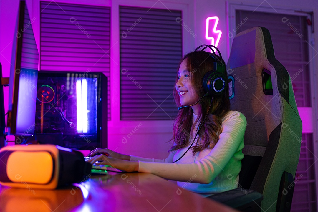 Jogador asiático jogando videogame online ganhando entusiasmo no PC com efeito de iluminação