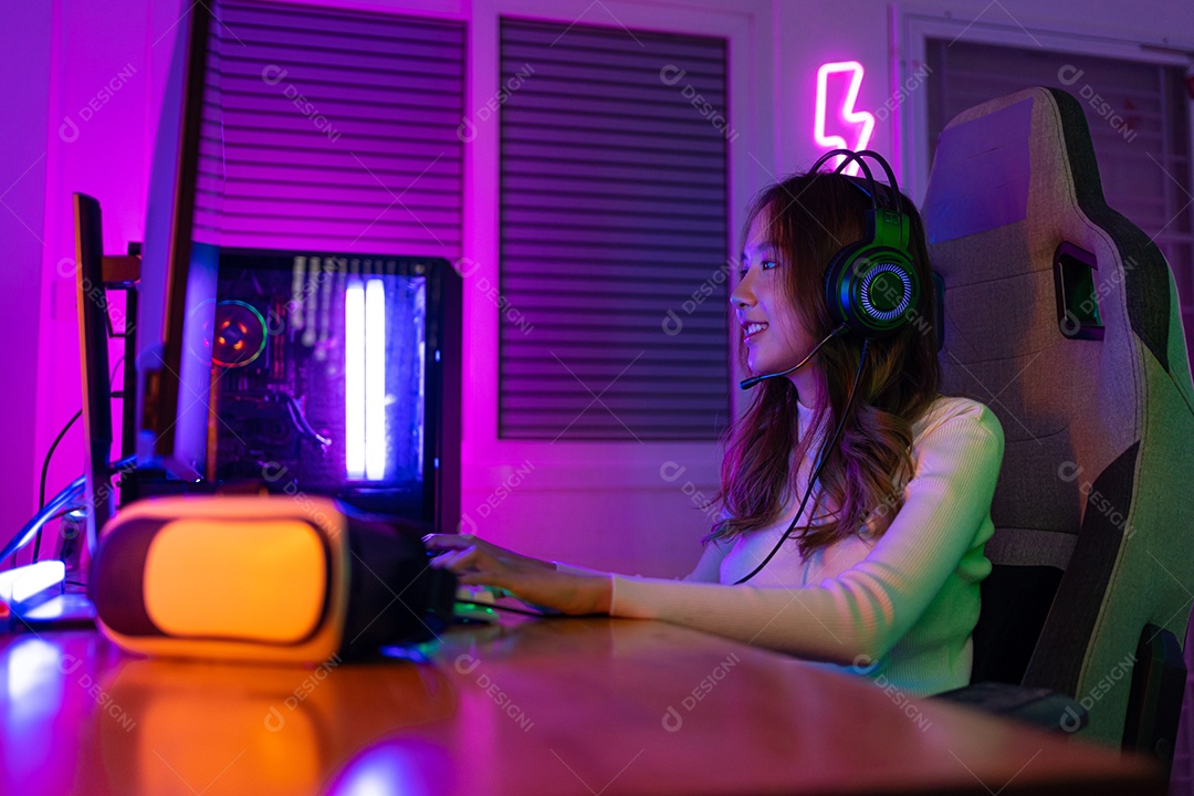 Jogador asiático jogando videogame online ganhando entusiasmo no PC com efeito de iluminação