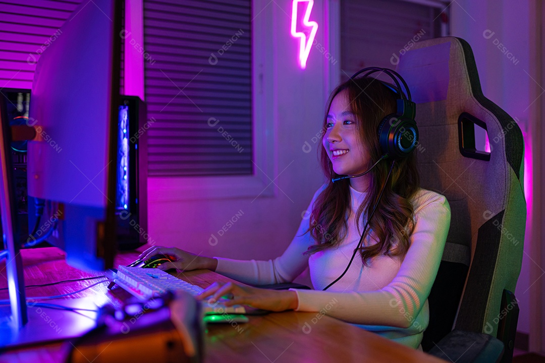 Jogador asiático jogando videogame online ganhando entusiasmo no PC com efeito de iluminação