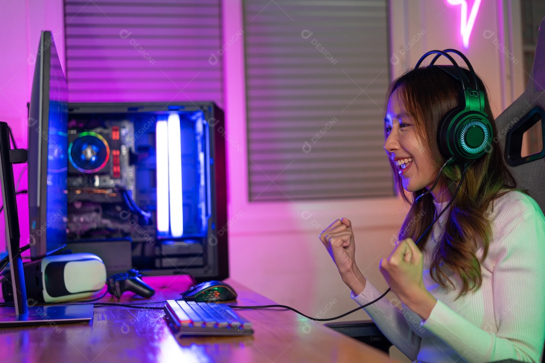 Jogador asiático jogando videogame online ganhando entusiasmo no PC com efeito de iluminação