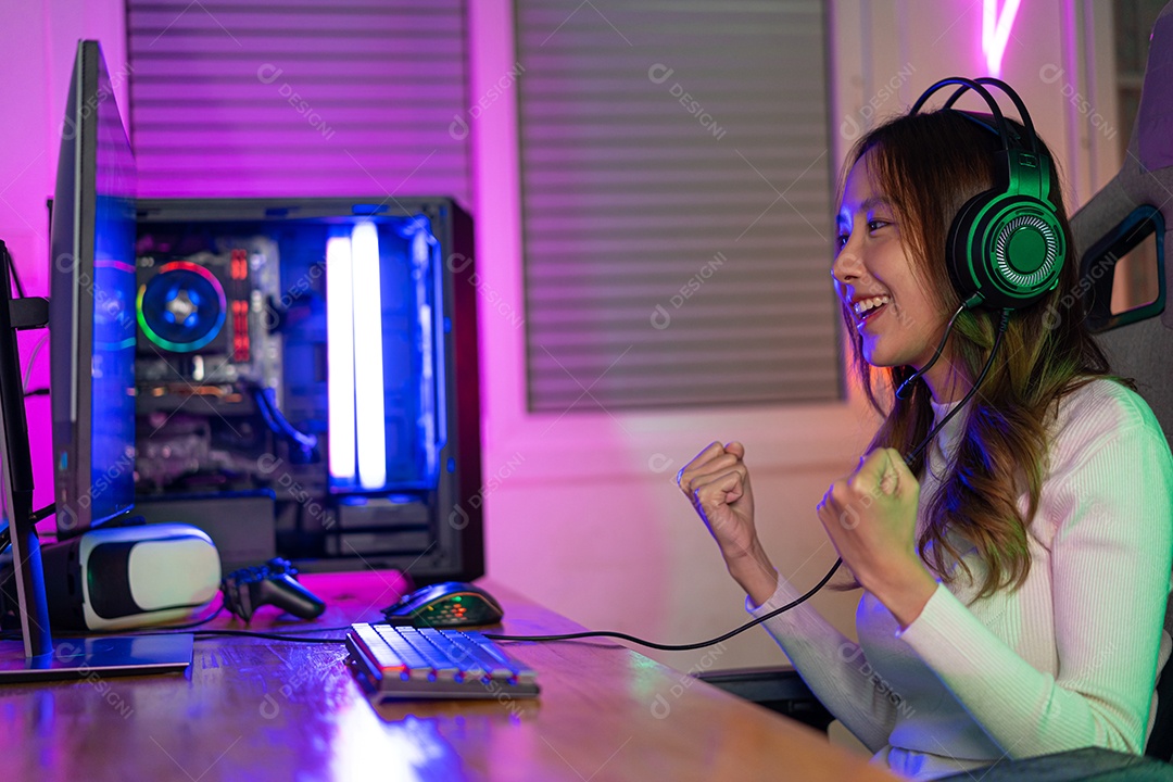 Jogador asiático jogando videogame online ganhando entusiasmo no PC com efeito de iluminação