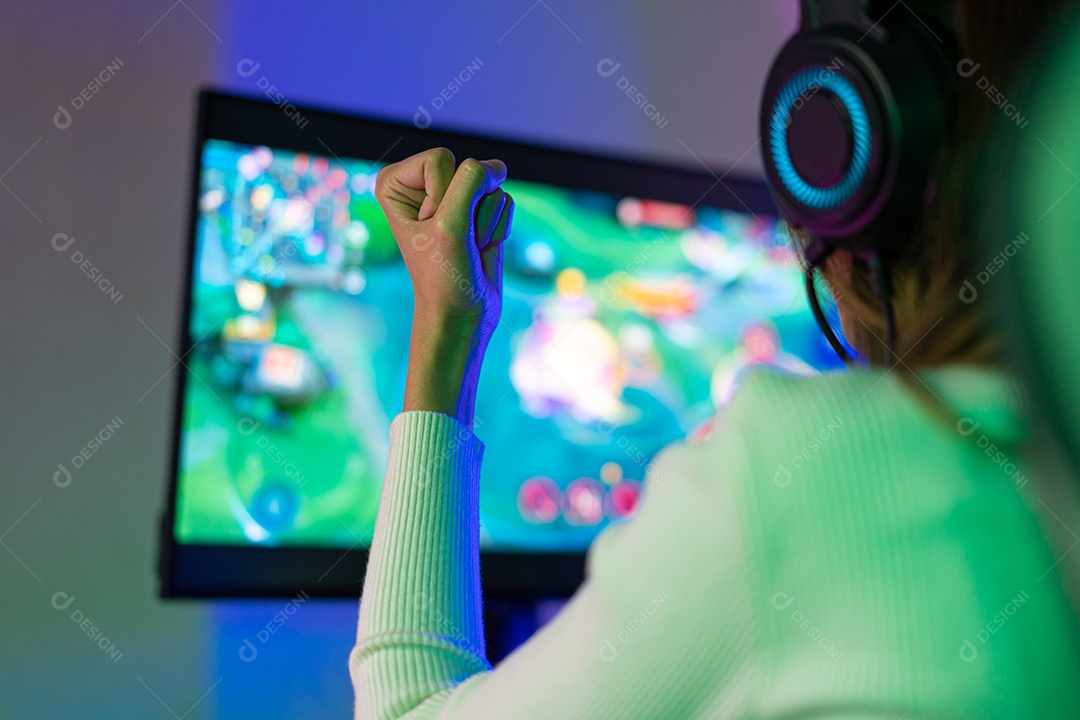 Jogador asiático jogando videogame online ganhando entusiasmo no PC com efeito de iluminação