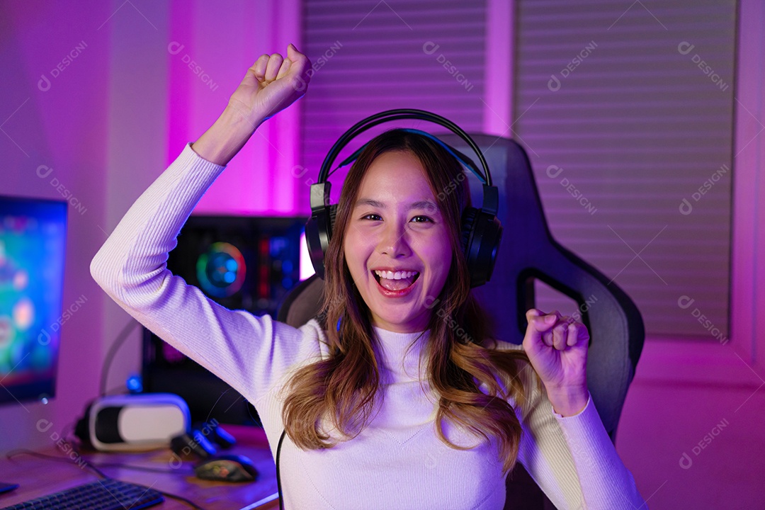Jogador asiático jogando videogame online ganhando entusiasmo no PC com efeito de iluminação