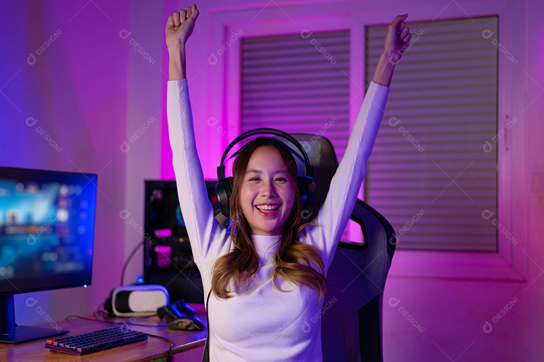 Jogador asiático jogando videogame online ganhando entusiasmo no PC com efeito de iluminação