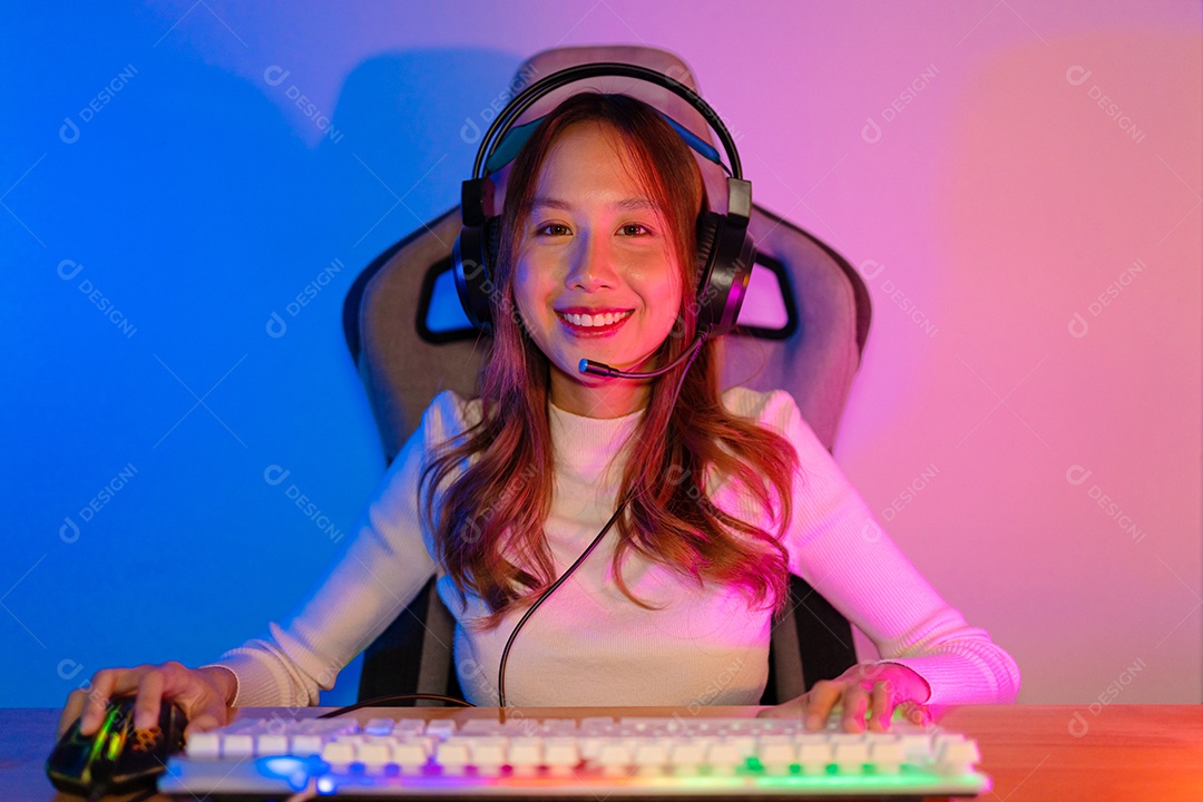 Jogador e E-Sport online de mulher asiática jogando videogame de computador online com efeito de iluminação, transmissão ao vivo em casa.