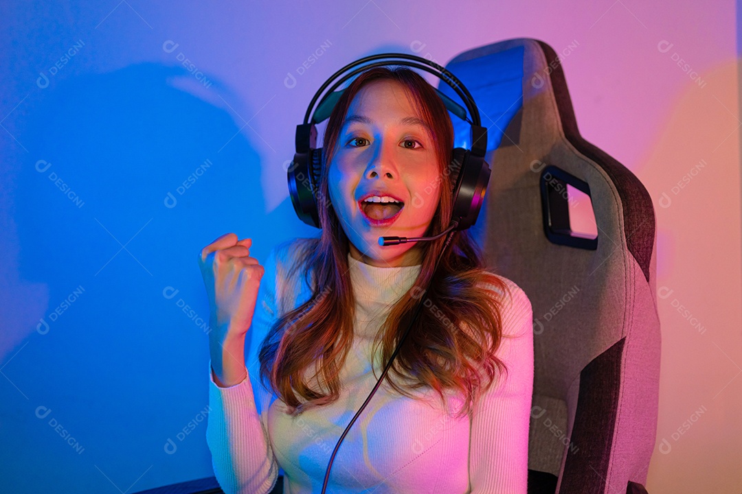 Jogador asiático jogando videogame online ganhando entusiasmo no PC com efeito de iluminação