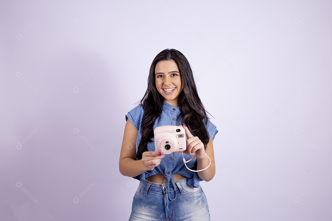 Linda mulher jovem segurando câmera fotográfica sobre fundo isolado branco