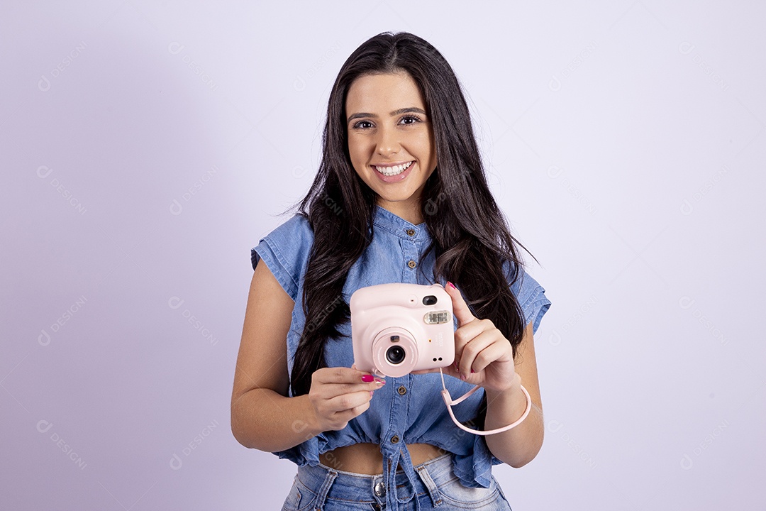 Linda mulher jovem segurando câmera fotográfica sobre fundo isolado branco