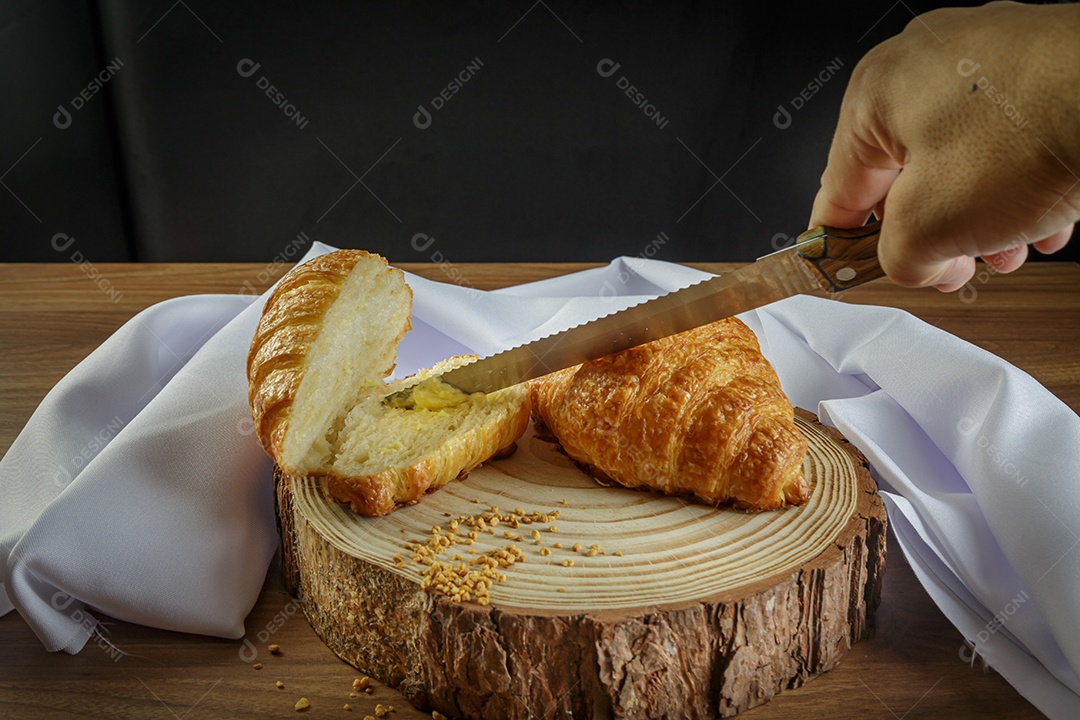 Deliciosos croissants em tronco de madeira, com toalha branca ao redor.