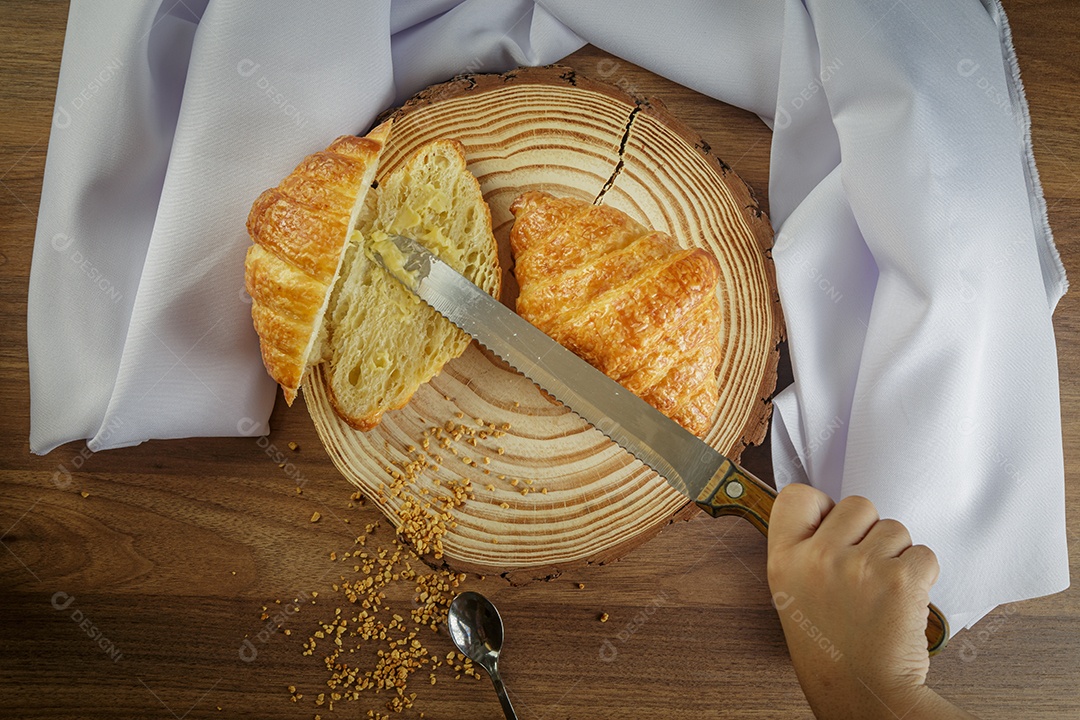 Deliciosos croissants em tronco de madeira, com toalha branca ao redor.