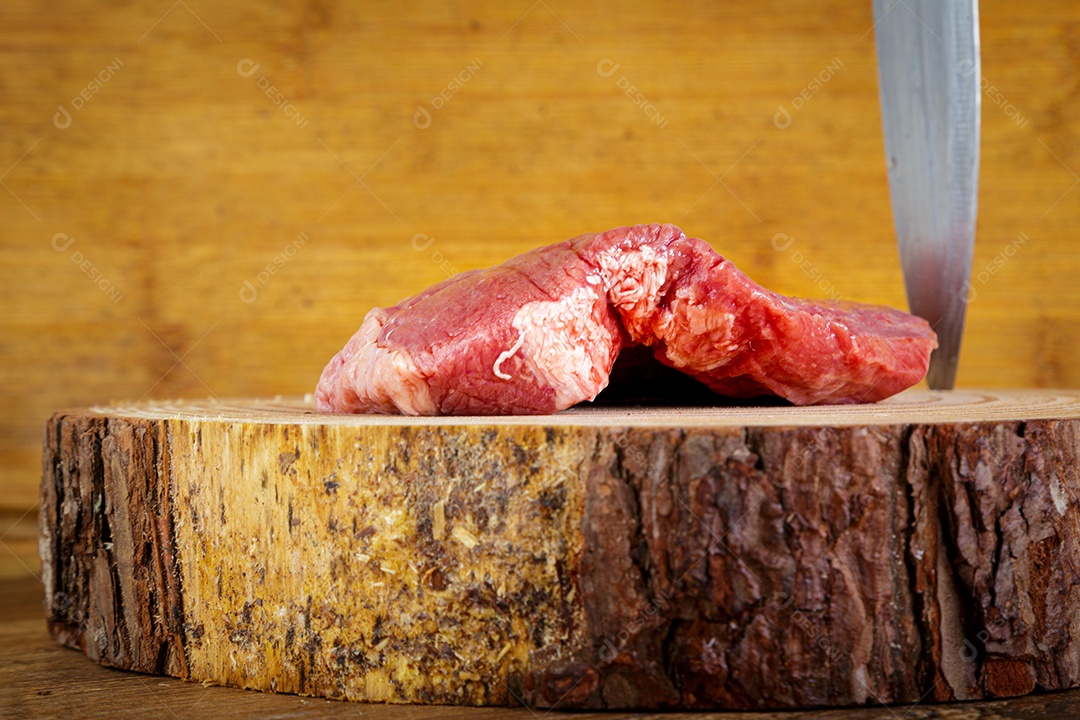 Bife de picanha cru em fundo de madeira em estilo rústico.