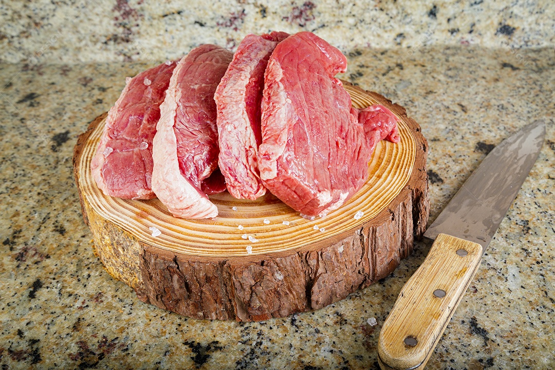 Bife de picanha cru em fundo de madeira em estilo rústico.