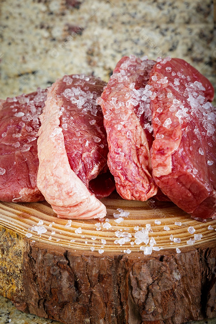 Bife de picanha cru em fundo de madeira em estilo rústico.