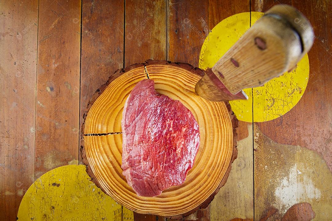 Bife de picanha cru em fundo de madeira em estilo rústico.