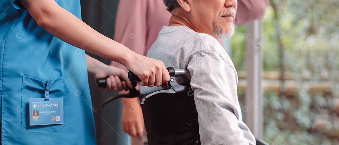 Enfermeira cuidadora asiática apoia idoso sênior em cadeira de rodas na sala de estar.
