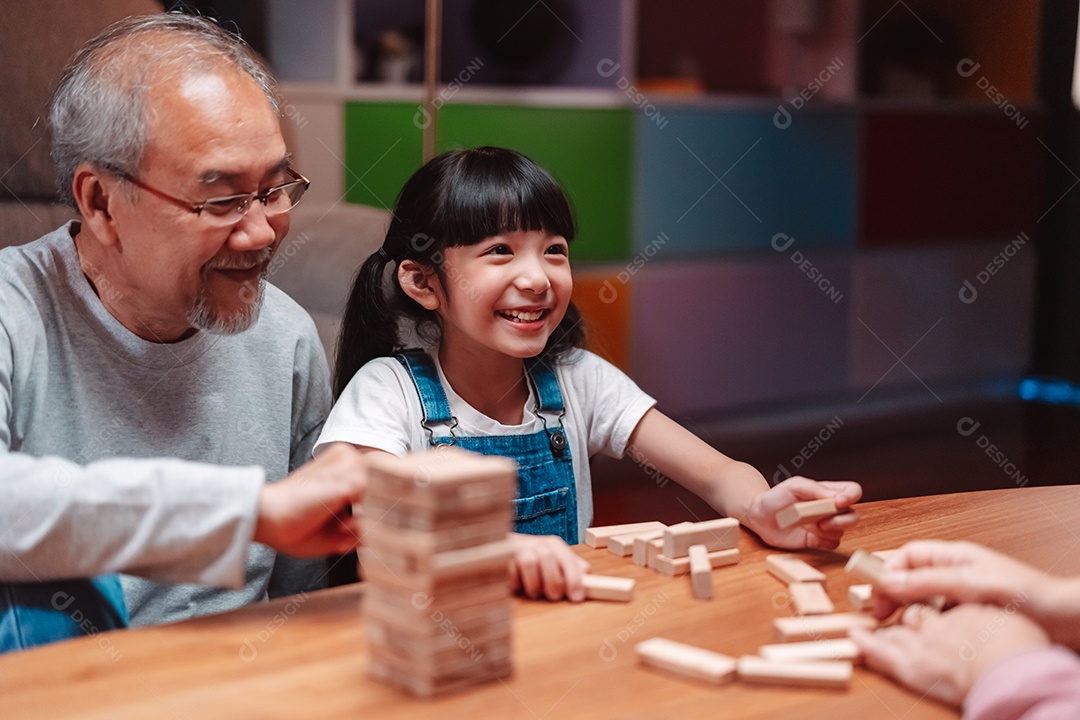 A família feliz asiática da filha joga bloco de madeira de brinquedo em casa.