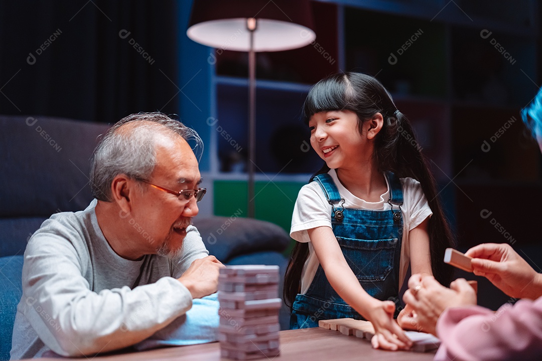 A família feliz asiática da filha joga bloco de madeira de brinquedo em casa.