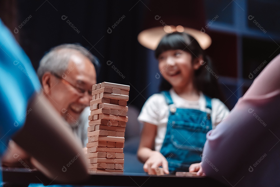 A família feliz asiática da filha joga bloco de madeira de brinquedo em casa.