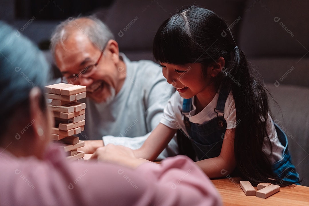 A família feliz asiática da filha joga bloco de madeira de brinquedo em casa.