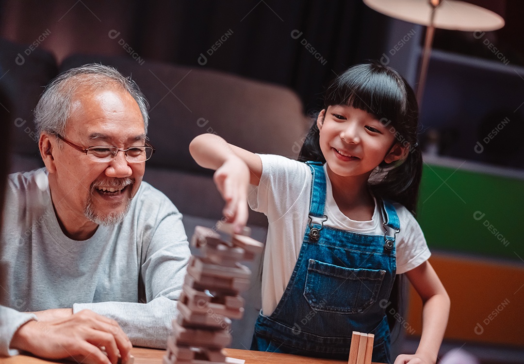 A família feliz asiática da filha joga bloco de madeira de brinquedo em casa.