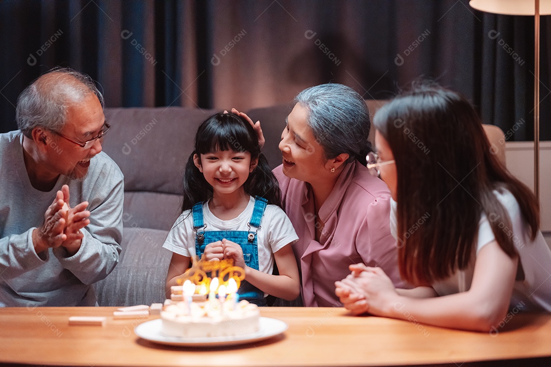 Família feliz asiática de garotinha soprando velas no bolo.