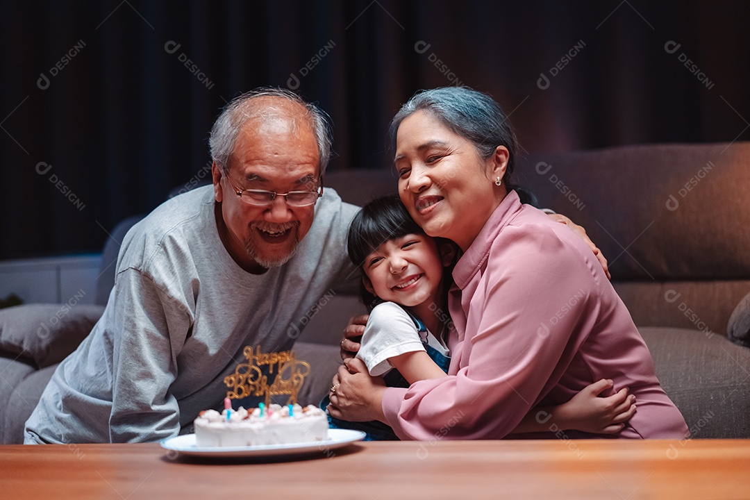 Família feliz asiática de garotinha soprando velas no bolo.