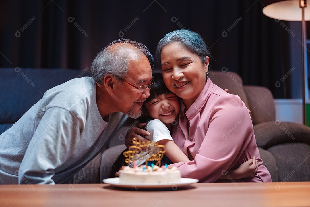 Família feliz asiática de garotinha soprando velas no bolo.
