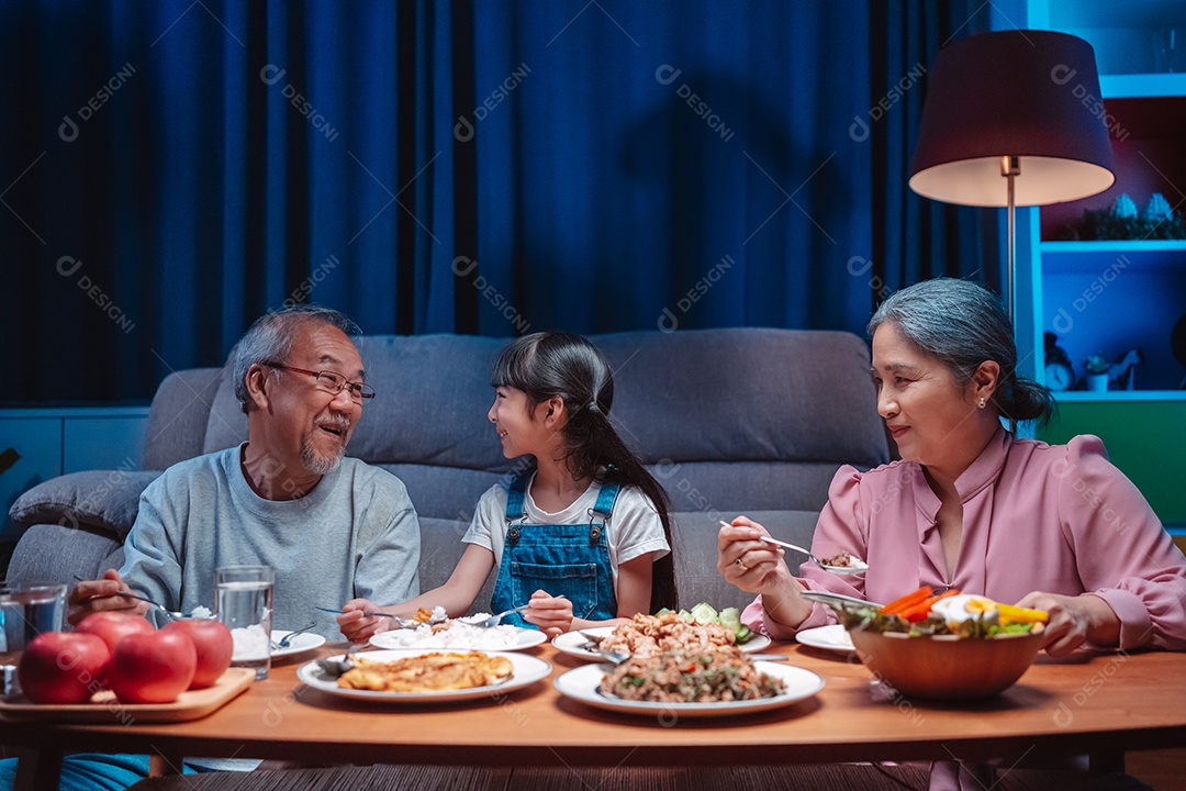 Família feliz asiática comendo na mesa japonesa de jantar sorrindo juntos.