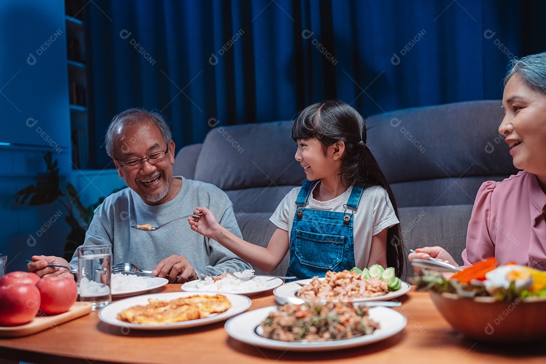 Família feliz asiática comendo na mesa japonesa de jantar sorrindo juntos.