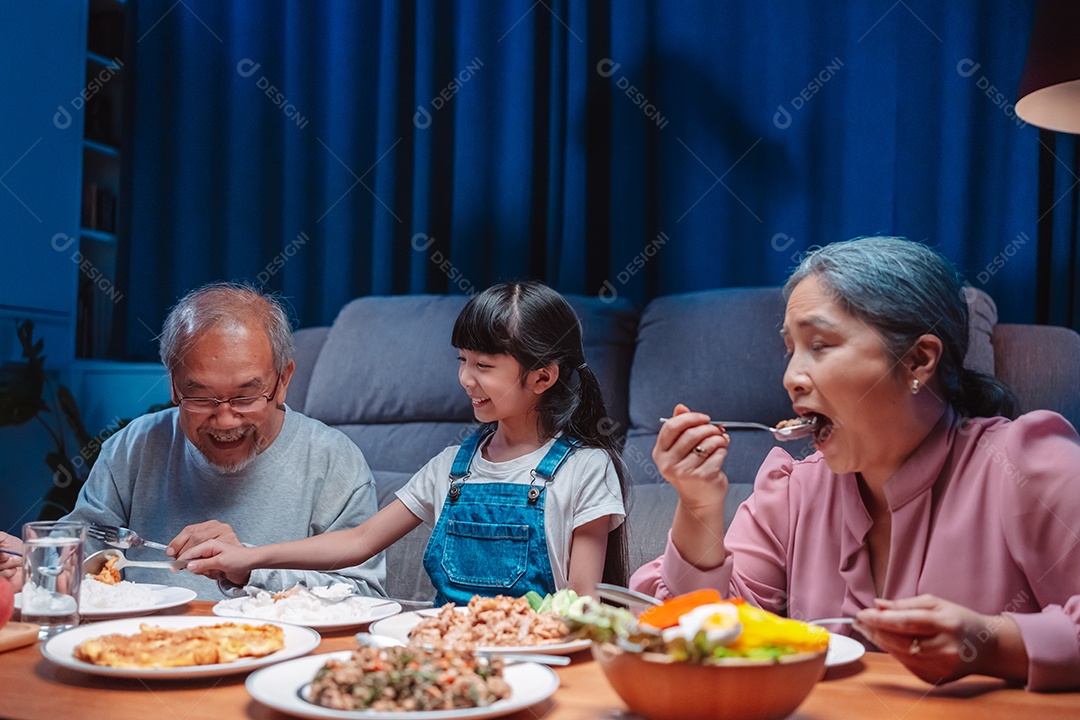 Família feliz asiática comendo na mesa japonesa de jantar sorrindo juntos.
